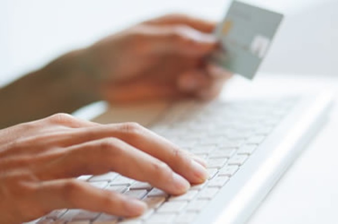 Accounts payable solution for business operation showing hand with credit card hovering above keyboard